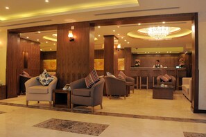 Una hall con reception, diverse zone salotto e un lampadario.
