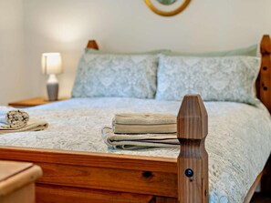 A neatly made bed with a patterned bedspread, a wooden headboard, and a bedside lamp. - 1 Bed in Malmesbury (oc-95500) (Malmesbury)