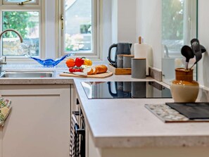 A modern kitchen with a sink, countertop, and various kitchen items including a cutting board, vegetables, and a coffee maker. - 1 Bed in Malmesbury (oc-95500) (Malmesbury)