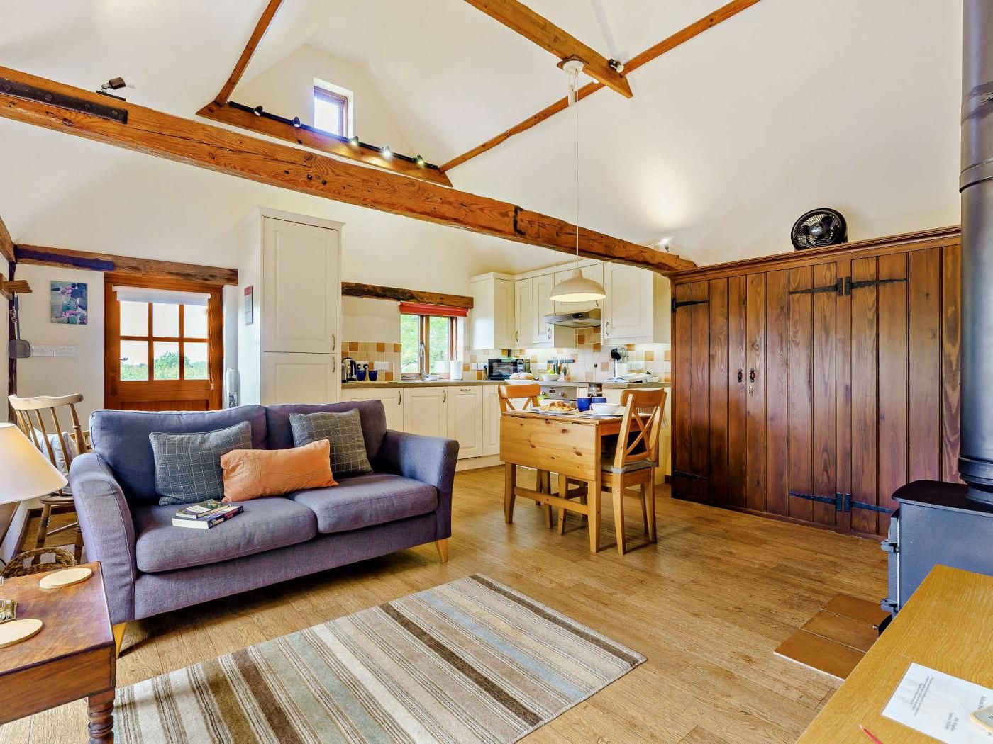 A spacious living area with a sofa, dining table, and kitchen in the background.