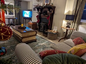 Een gezellige woonkamer met een open haard, een televisie en gestreepte banken.