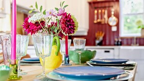 Ein Esstisch mit einer Blumenvase, klaren Gläsern und blauen Tellern.