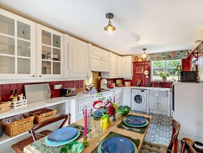 A kitchen with white cabinets, a washing machine, and a dining area with a table set for four. - 2 Bed in Hemel Hempstead (oc-95536) (Great Gaddesden)