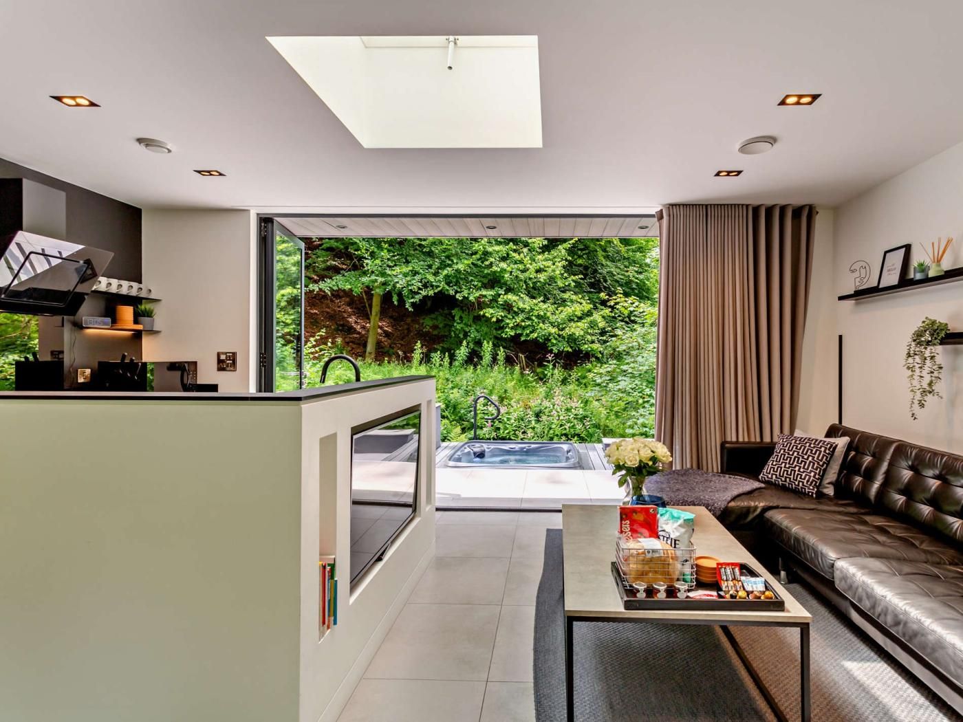 A modern living room with a sofa, coffee table, and a view of a lush garden.