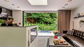A modern living room with a sofa, coffee table, and a view of a lush garden.