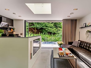 A modern living room with a sofa, coffee table, and a view of a lush garden.