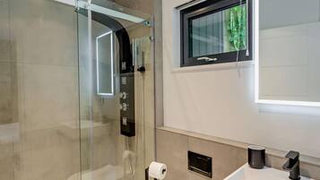 A modern bathroom with a glass-enclosed shower, a toilet paper holder, a window with a view, and a sink with a faucet.