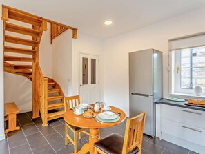 A kitchen with a built-in refrigerator, a dining table with chairs, and a wooden staircase.
