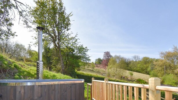 A wooden deck with a hot tub, wooden railings, and a view of a green landscape. - 2 Bed in Corwen (oc-95542) (Corwen)