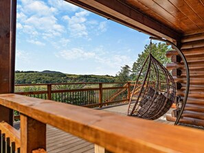 Une terrasse en bois avec une balançoire suspendue, offrant une vue imprenable sur un paysage magnifique.