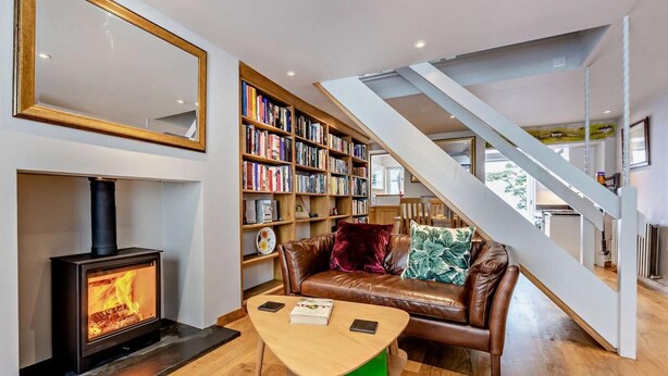 Ein modernes Wohnzimmer mit Kamin, einer Ledersofa, einem Holztisch und einem Bücherregal.