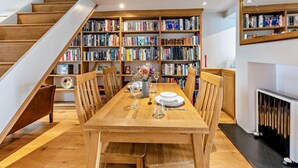Ein Essbereich mit Holztisch, Stühlen, einem Bücherregal und einer Treppe.