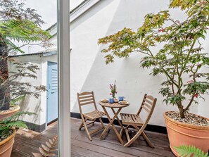 An outdoor seating area with a table and two chairs, surrounded by potted plants. - 1 Bed in Bideford (oc-wader) (Appledore)