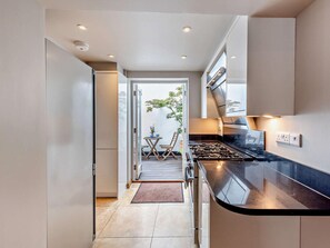 Eine moderne Küche mit schwarzem Arbeitsplatz, Edelstahlgeräten und Blick auf einen Balkon mit Gartenmöbeln.