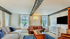 Ein Wohnzimmer mit einer Couch, einem Holztisch und einem Fernseher.