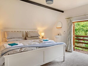 A bedroom with a bed, bedside tables, a nightstand, a mirror, and a view of greenery through a window. - 6 Bed in Taunton (oc-95371) (Sampford Brett)