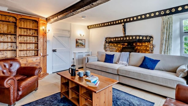 Ein gemütliches Wohnzimmer mit Kamin, einer Couch, einem Couchtisch und einem Ledersessel.