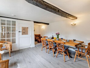 A dining area with a wooden table and chairs, a white door with glass panels, and a light fixture on the wall. - 6 Bed in Taunton (oc-95371) (Sampford Brett)