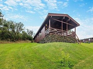 A building with a sloped roof, stone foundation, and a grassy hill surrounding it. - 3 Bed in Aberdovey (oc-95594) (Aberdovey)