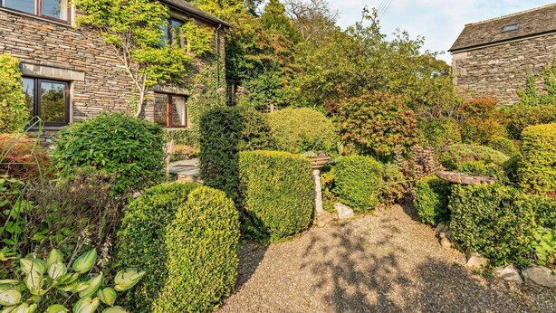 A stone house with a garden, a gravel path, and a small pond. - 4 Bed in Kendal (oc-95607) (Crosthwaite)