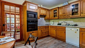 A kitchen with wooden cabinets, a microwave, oven, and dishwasher. - 4 Bed in Kendal (oc-95607) (Crosthwaite)