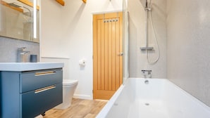 Un baño moderno con bañera, inodoro y tocador con cajones.