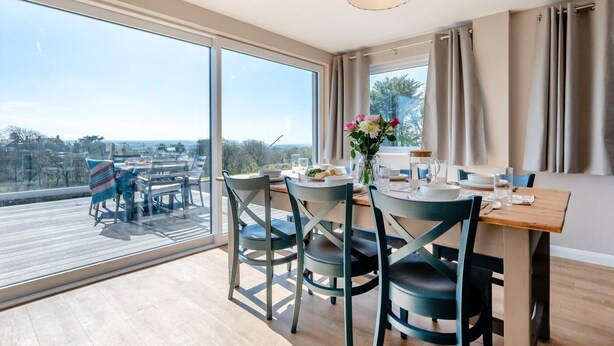 Un comedor con vistas a la ciudad, una mesa de madera y sillas.
