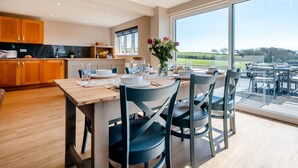 Una cocina moderna con armarios de madera, una mesa de comedor para cuatro personas y un ventanal con vistas al exterior.