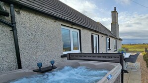 Un área de spa con una bañera de hidromasaje, asientos al aire libre y vistas al campo.