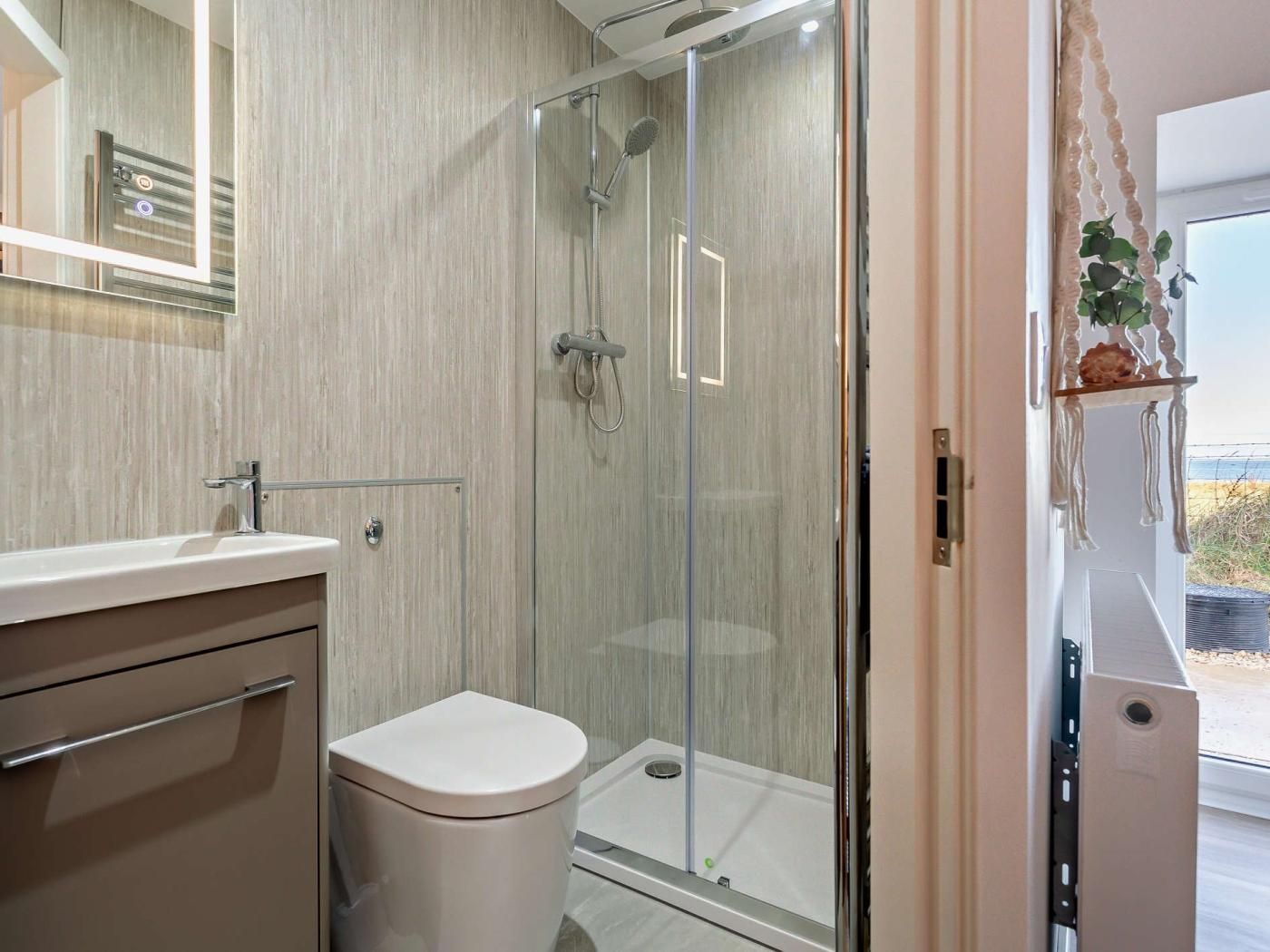 A modern bathroom with a glass shower enclosure, a toilet, and a vanity with a mirror.