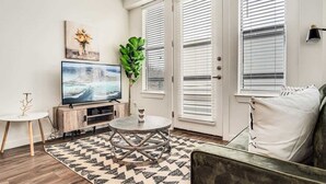 Un salon avec un téléviseur, une table basse ronde, un canapé et une plante en pot.
