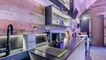 A modern kitchen with a black countertop, a compost bin, and a coffee machine.
