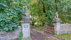 A pathway leading to a gated area with stone statues and a plaque on a stone pillar. - 1 Bed in Kirkby Stephen (oc-95627) (Ravenstonedale)