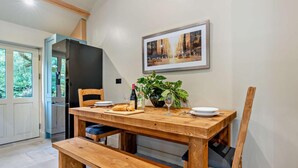 A dining area with a wooden table, chairs, a bench, a potted plant, and a framed picture on the wall. - 1 Bed in Kirkby Stephen (oc-95627) (Ravenstonedale)