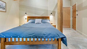 A bedroom with a wooden bed frame, a headboard, and a blue bedspread. - 1 Bed in Kirkby Stephen (oc-95627) (Ravenstonedale)