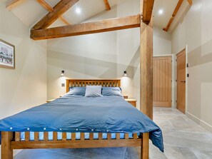 Ein Schlafzimmer mit einem Bettgestell aus Holz, einer Kopfstütze und einer blauen Bettdecke.