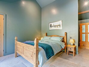 Ein Schlafzimmer mit einem hölzernen Bett, einem Nachttisch mit Lampe und einem gerahmten Bild an der Wand.