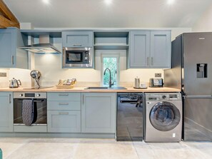 A modern kitchen with grey cabinets, a stainless steel microwave, a built-in oven, a dishwasher, and a washing machine. - 1 Bed in Kirkby Stephen (oc-95629) (Ravenstonedale)