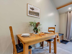 A dining table with chairs, a vase with flowers, a bottle, and a loaf of bread. - 1 Bed in Kirkby Stephen (oc-95629) (Ravenstonedale)