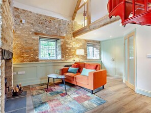 A cozy living room with a stone wall, a wooden ceiling, a red staircase, and a sofa with cushions. - 1 Bed in Wedmore (oc-95582) (Theale)