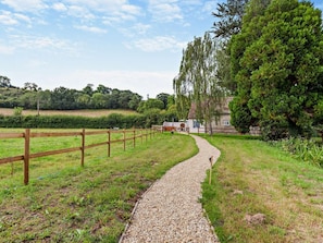A gravel path leading to a house with a fenced yard and a view of a hill. - 1 Bed in Wedmore (oc-95582) (Theale)
