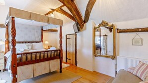 Una stanza con un letto a baldacchino, uno specchio e un termosifone.