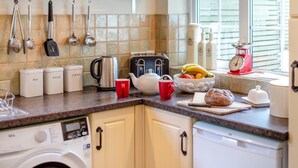 Een keuken met een wasmachine, een broodrooster, een waterkoker en een schaal met fruit.