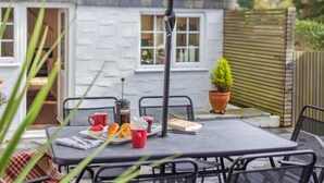 Een terras met een tafel, stoelen, een koffiepot en een boek.