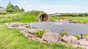 Ein rustikales Steinhaus mit rundem Eingang, umgeben von einer Schotterterrasse mit Außenbestuhlung.