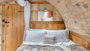 Ein gemütliches Zimmer mit einem hölzernen Bett, einer Backsteinwand und einer Holztür.