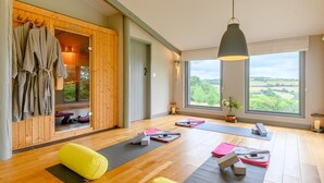 Ein Yoga-Raum mit Matten, einer Holzsauna und einem großen Fenster mit Blick.