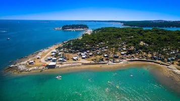Eine Vogelperspektive einer Küstenregion mit Strand, Campingplätzen und einer kleinen Insel.