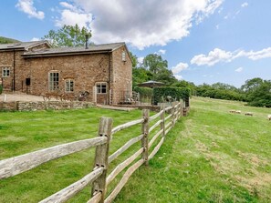 A stone building with a wooden fence in a grassy field. - 1 Bed in Hereford (oc-42897) (Craswall)
