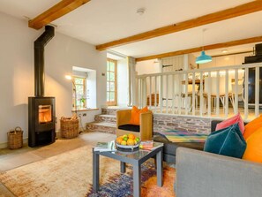 A cozy living room with a stone fireplace, a comfortable sofa, and a dining area with natural light. - 1 Bed in Hereford (oc-42897) (Craswall)